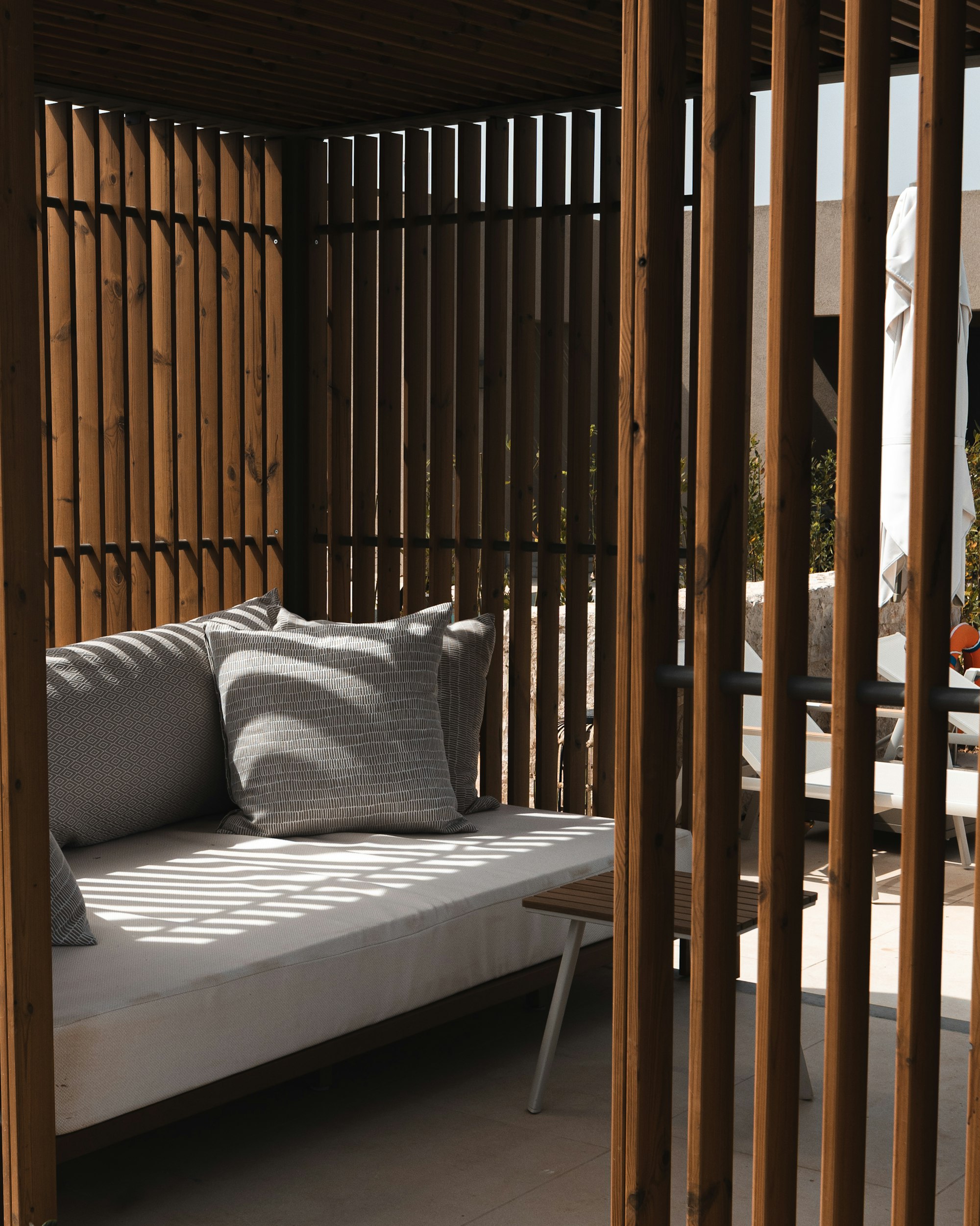 Lounge mit grauen Polstern hinter Holzlamellen