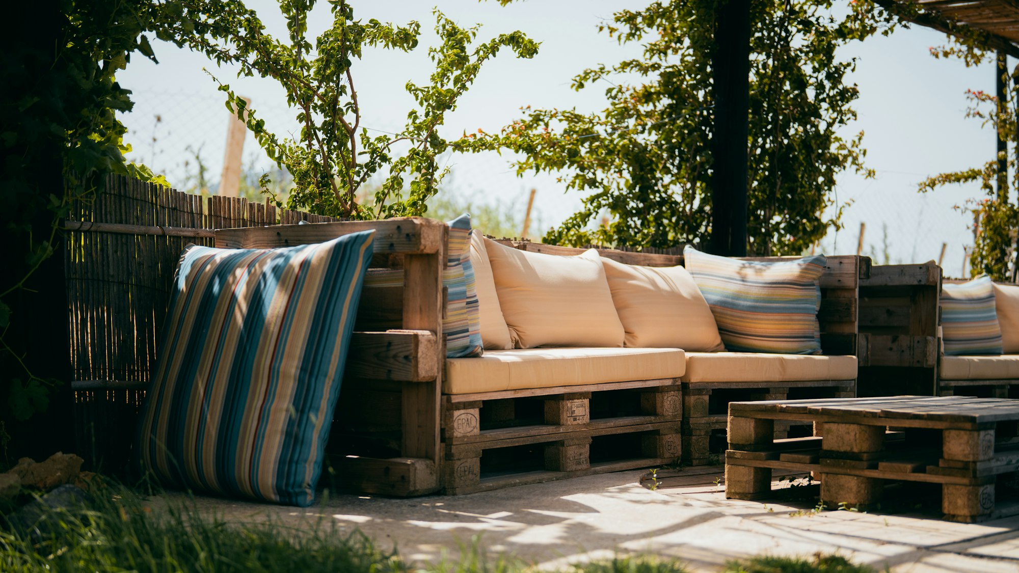 Selbstgebaute Lounge aus Paletten mit Polstern auf einer Terrasse